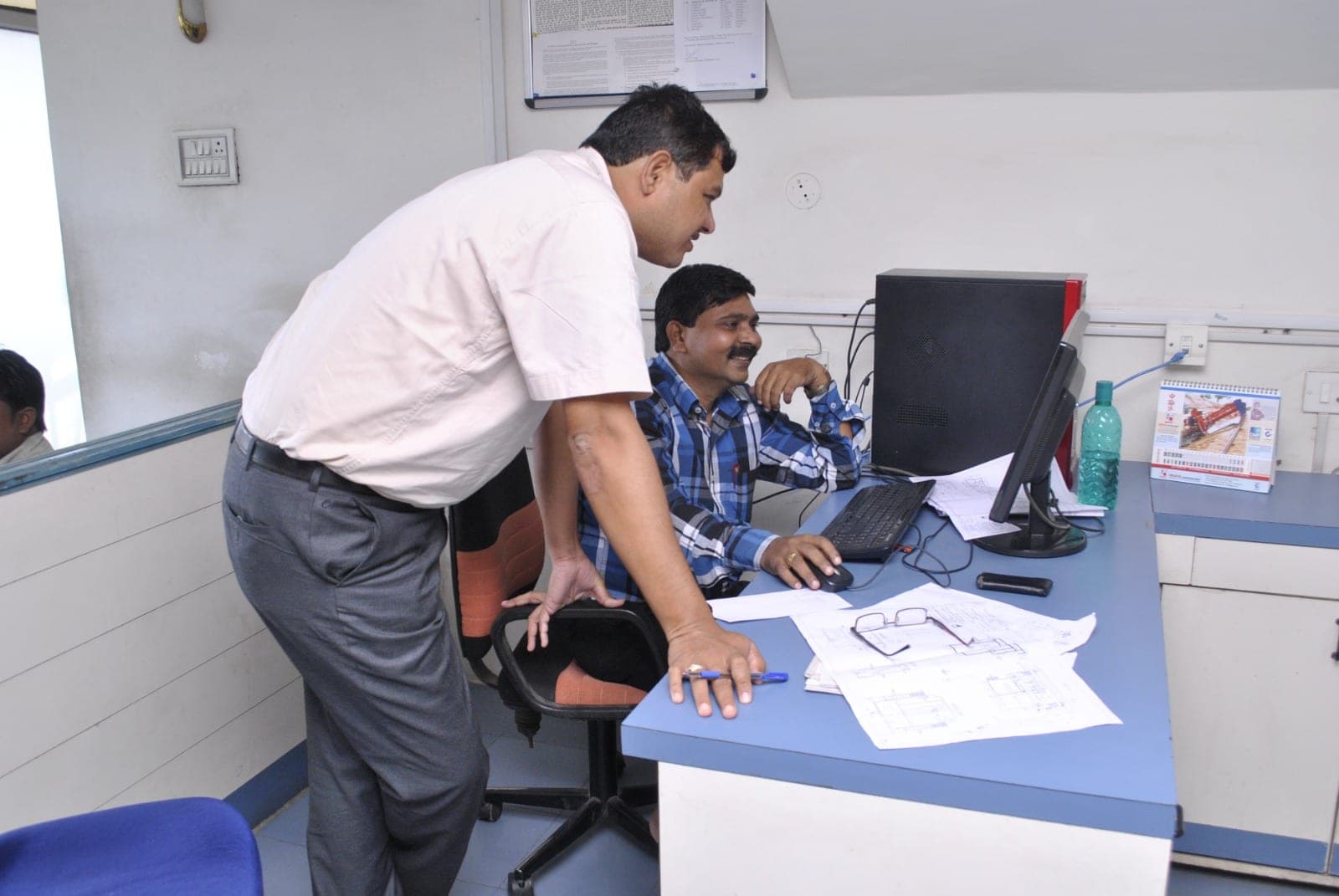 A senior Gondwana engineer reviewing design drawings with a colleague at a CAD workstation