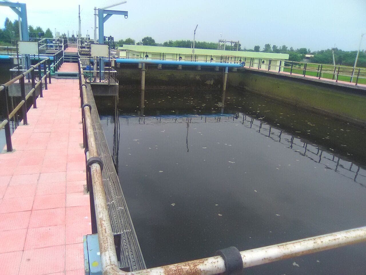 Settling tank with perimeter walkway, railings, and inlet distribution piping at the 10 MLD Jalandhar STP, Punjab