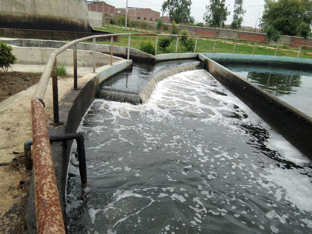 Treated effluent cascading over a weir channel between process units at the 50 MLD Jalandhar STP, Punjab