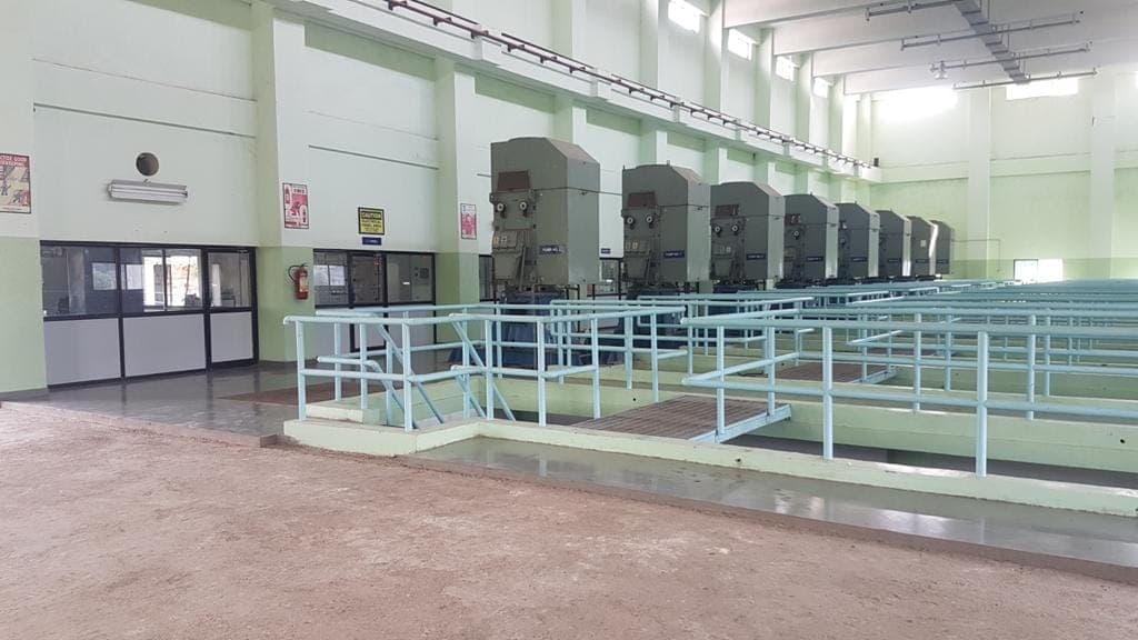 Interior of the Mundhwa pumping station hall showing a row of vertical pump units alongside handrailed channels