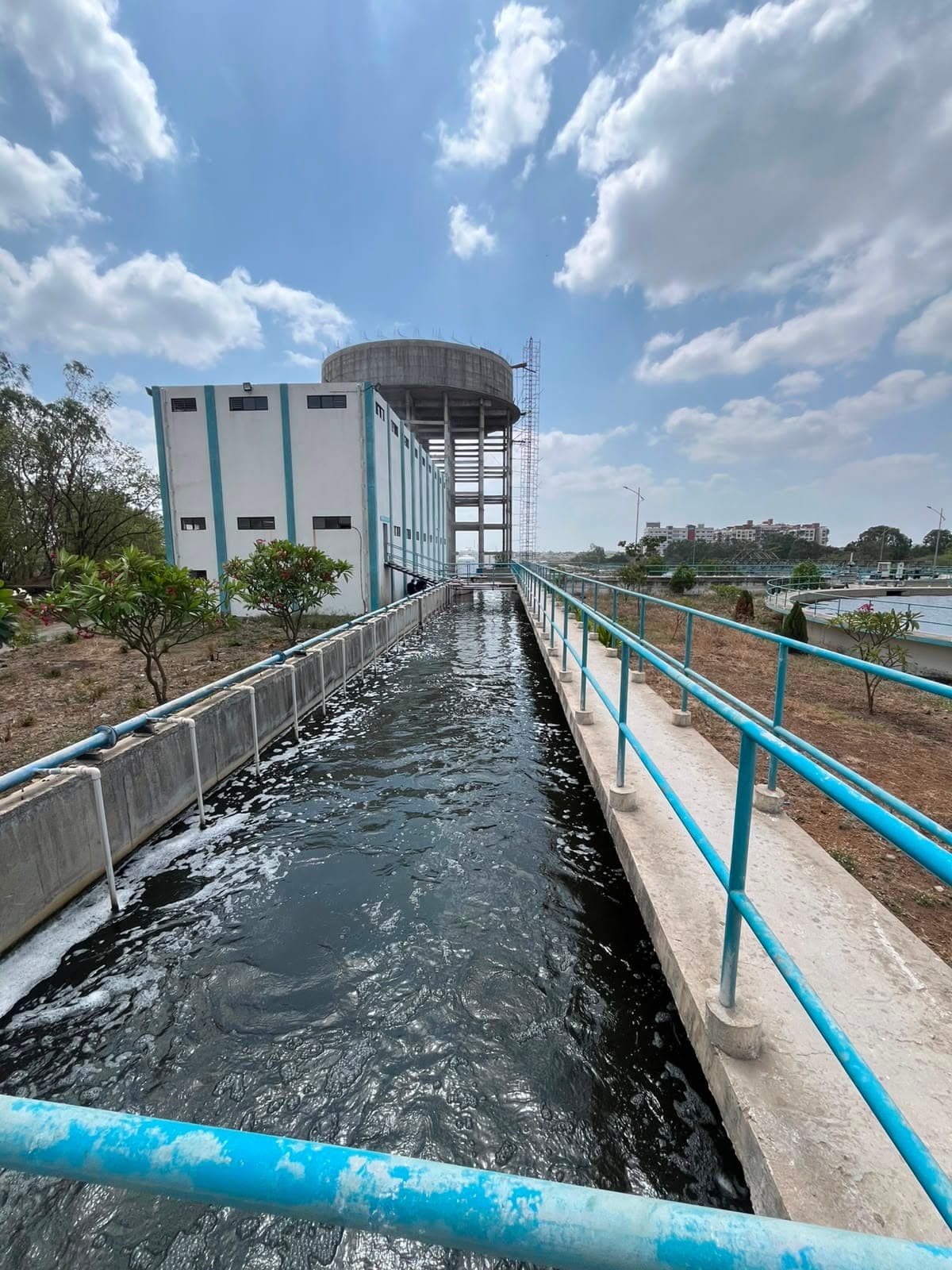 Treated-water channel running alongside an elevated service reservoir and pump house at the PCMC 100 MLD water treatment plant