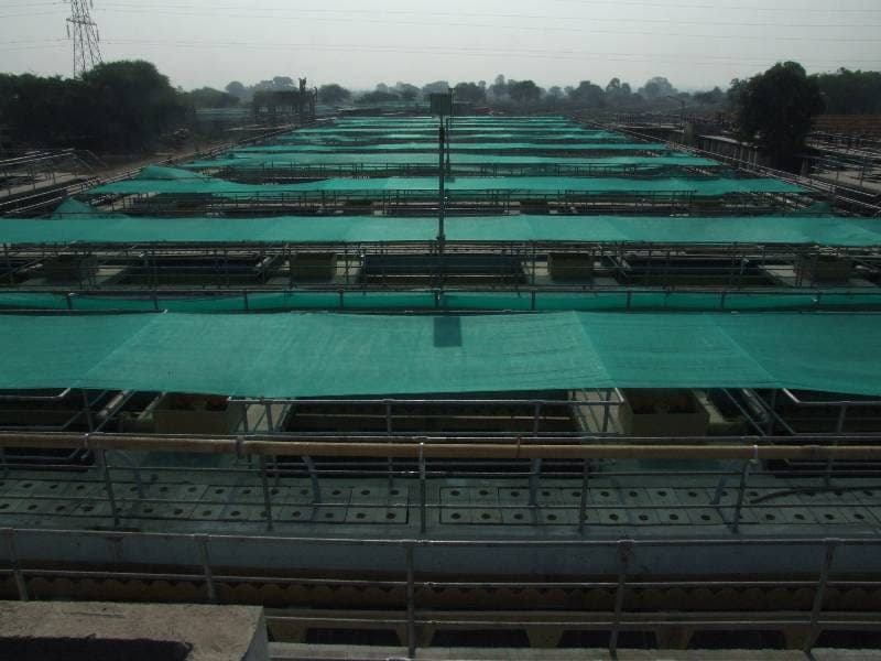Elevated view across the shade-net-covered aeration tanks and process galleries of the Tapovan STP, Nashik