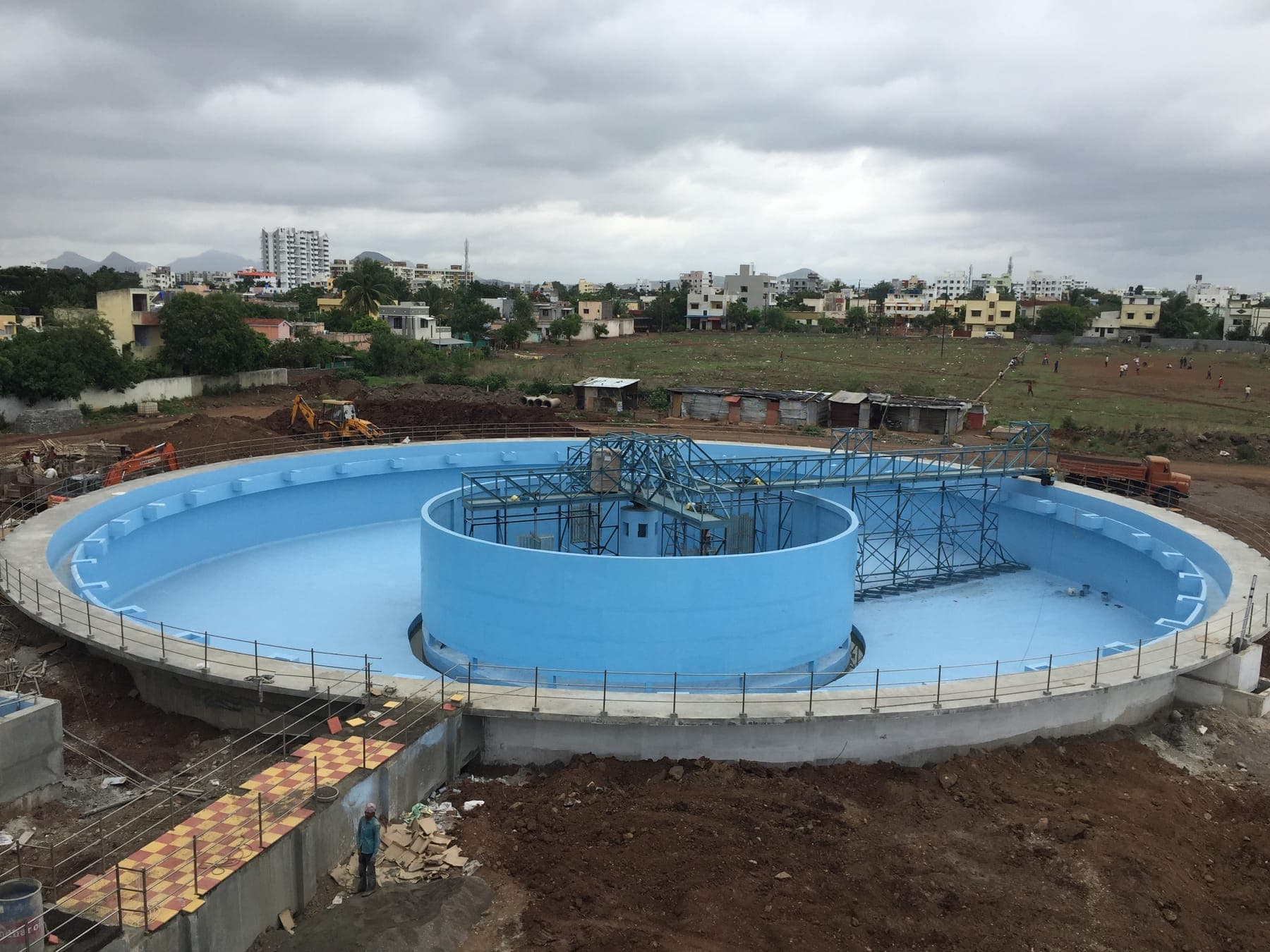 Circular clarifier with freshly epoxy-coated tank walls and central drive structure during construction at the Tapovan STP, Nashik